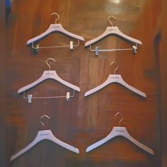 four white hangers are hanging on a wooden table