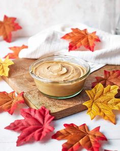 a jar of peanut butter sitting on top of a cutting board surrounded by fall leaves