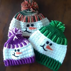 three knitted hats with snowmen on them sitting on a wooden floor next to each other