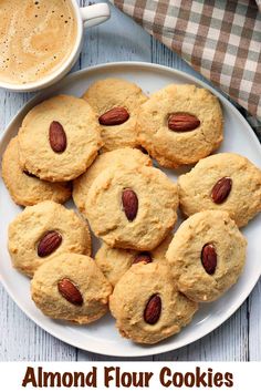 a white plate topped with cookies and almonds next to a cup of coffee