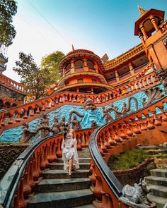 a woman is walking down the stairs in front of a building with elaborate carvings on it