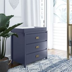 a blue dresser sitting on top of a wooden floor next to a potted plant