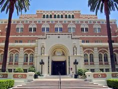 a large building with steps leading to it and palm trees in the foreground on a sunny day