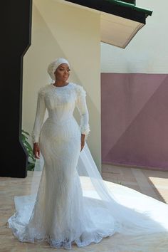 a woman in a white wedding dress and veil standing on a floor next to a building