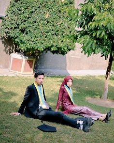 a man and woman sitting on the grass