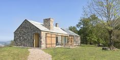 a small stone house sitting on top of a lush green field