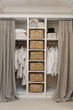 an organized closet with linens, clothes and wicker baskets on the bottom shelf