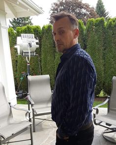 a man standing in front of a camera on top of a patio next to lawn chairs