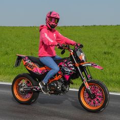 a person on a pink and orange dirt bike in the middle of an open road