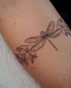 a dragonfly sitting on top of a flower tattoo