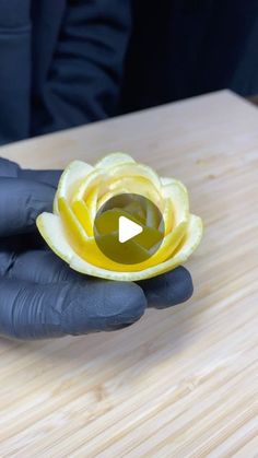 a person in black gloves holding a yellow flower