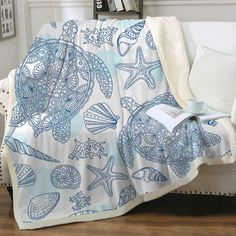 a blue and white blanket sitting on top of a couch next to a book shelf