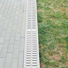 a metal grate sitting on top of a green grass covered field next to a sidewalk