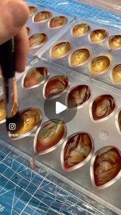 a person is making cupcakes with icing and gold leaf designs on them