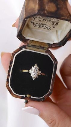 someone is holding an old diamond engagement ring in their hand and it's inside the box