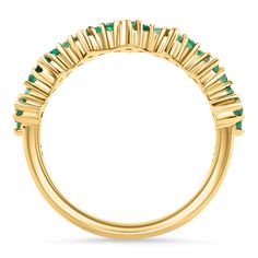 a yellow gold ring with emerald stones on the sides and an open band around it