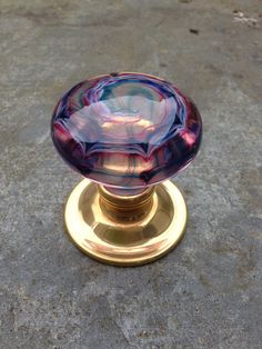 a purple glass door knob sitting on top of a sidewalk