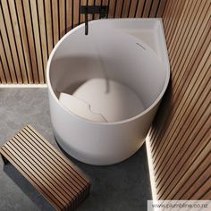 a large white bath tub sitting on top of a floor next to a wooden wall