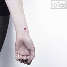 a woman's hand with a small red dot tattoo on it