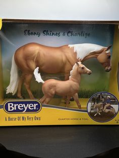 a toy horse and foal in its box on a table with it's mother