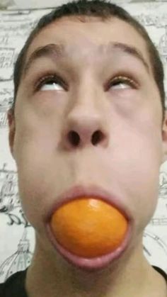 a man with an orange in his mouth