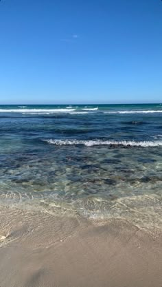 the ocean is clear and blue with waves coming in from the shore on a sunny day