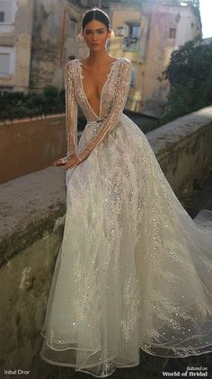 a woman in a long white dress standing on a ledge with her hands on her hips