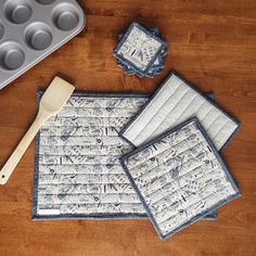 three placemats and two muffin tins on a wooden table with baking utensils