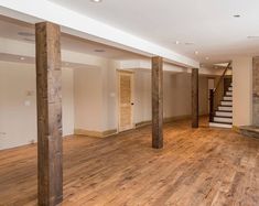 an empty living room with wood floors and stone fireplace in the center, surrounded by columns