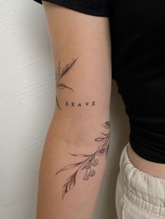 a woman with a tattoo on her arm that reads brave and has flowers growing out of it