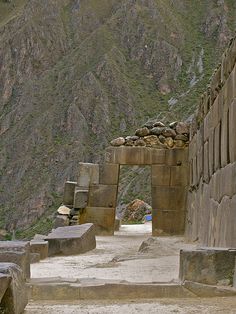 an old stone building with mountains in the background