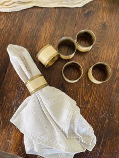 some napkins and other items on a wooden table with gold rings around them for decoration