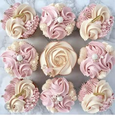 cupcakes decorated with pink and white icing on a marble surface, top view