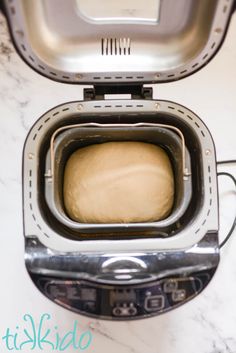 an open toaster sitting on top of a white counter next to a piece of bread