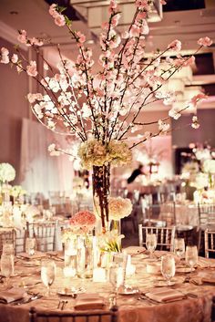 an elegant centerpiece with flowers and candles is displayed on a round table in the ballroom