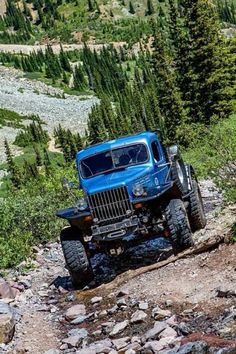 a blue truck driving down a rocky road