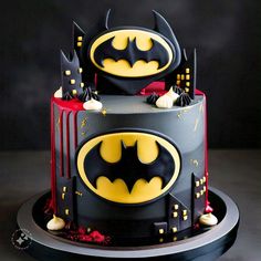 a batman themed birthday cake with red and black icing on it's sides