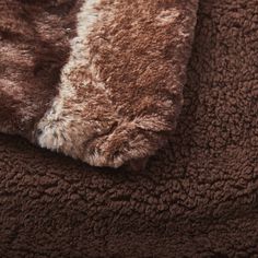 a brown and white cat sleeping on top of a fluffy bed cover with fur covering it's back