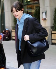 a woman walking down the street carrying a black purse