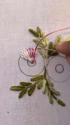 someone is stitching flowers on a piece of fabric