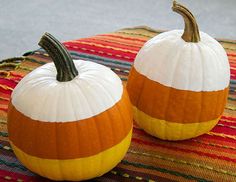 two painted pumpkins sitting on top of a colorful table cloth covered in stripes and circles