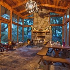 the inside of a house with large windows and stone flooring is lit by a chandelier