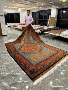 a man standing next to a pile of rugs