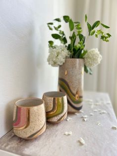 three vases with flowers in them are sitting on a table next to a wall