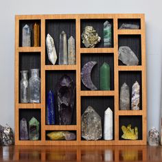 a wooden shelf filled with different types of rocks and crystals on top of a table