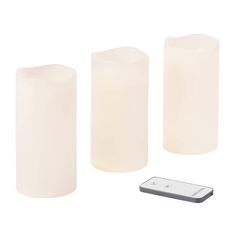 three white candles and a remote control on a white background