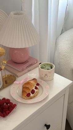 a white table topped with a croissant and raspberries