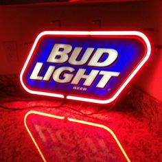 bud light neon sign sitting on top of a red counter next to a white wall