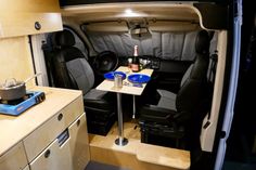 the interior of a camper van with two tables and chairs on each side of the room