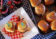 two trays filled with mini sandwiches on top of a blue and white checkered table cloth